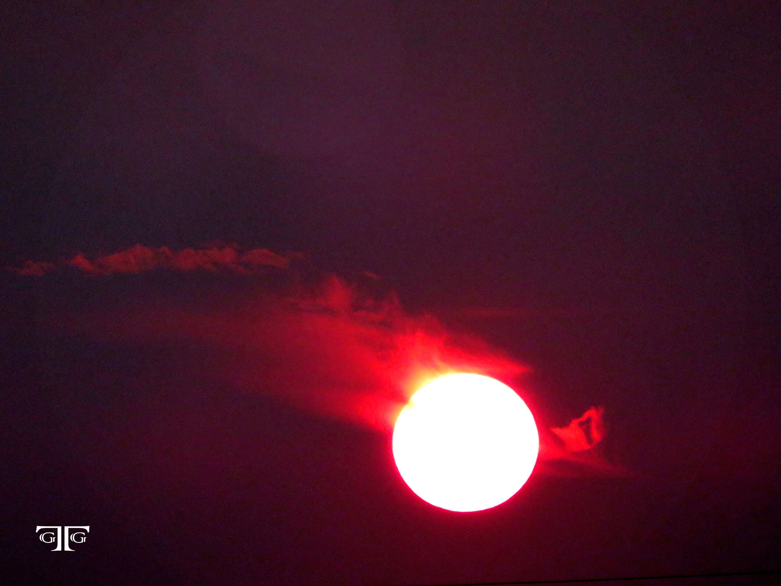 A red sun is seen in the dark sky.