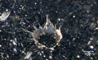 CIMG7240 A bullet hole in the ground with water drops coming from it.
