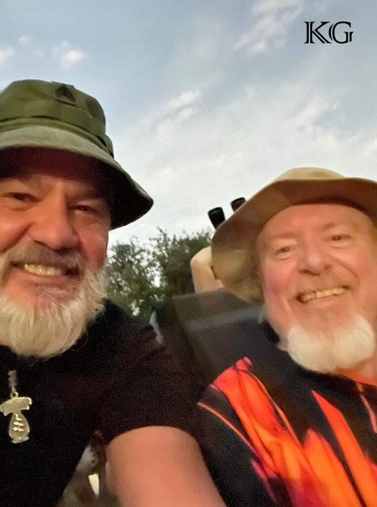 Two older men with beards and hats smiling for a picture.