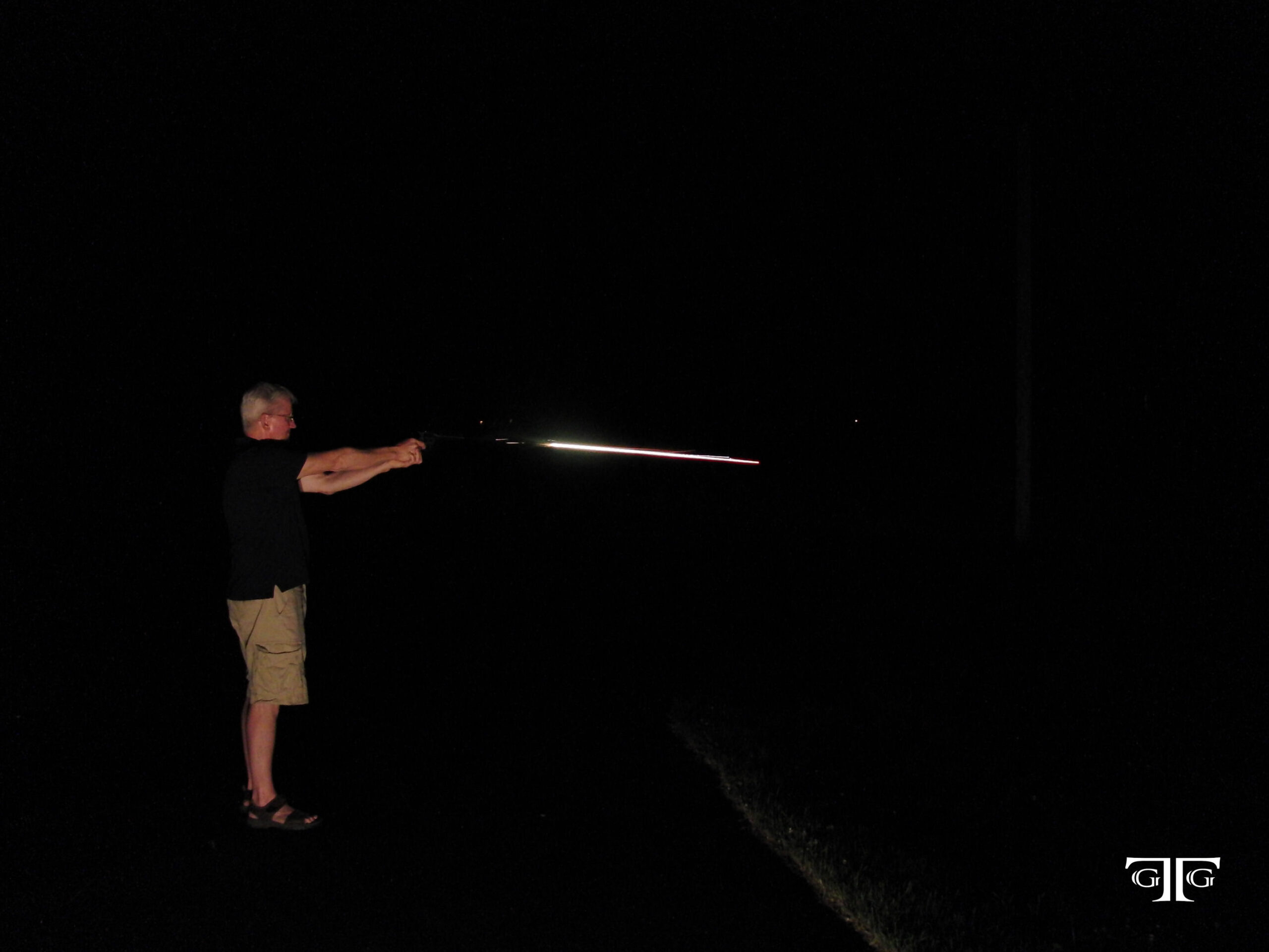 CIMG6540 with GTG logo A man holding a baseball bat in the dark.