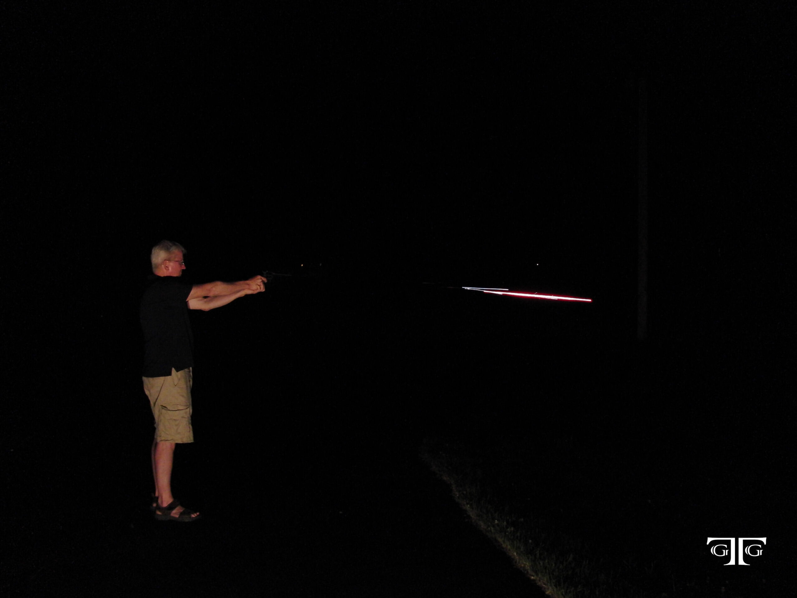 CIMG6541 with GTG logo A man standing in the dark holding a bat.