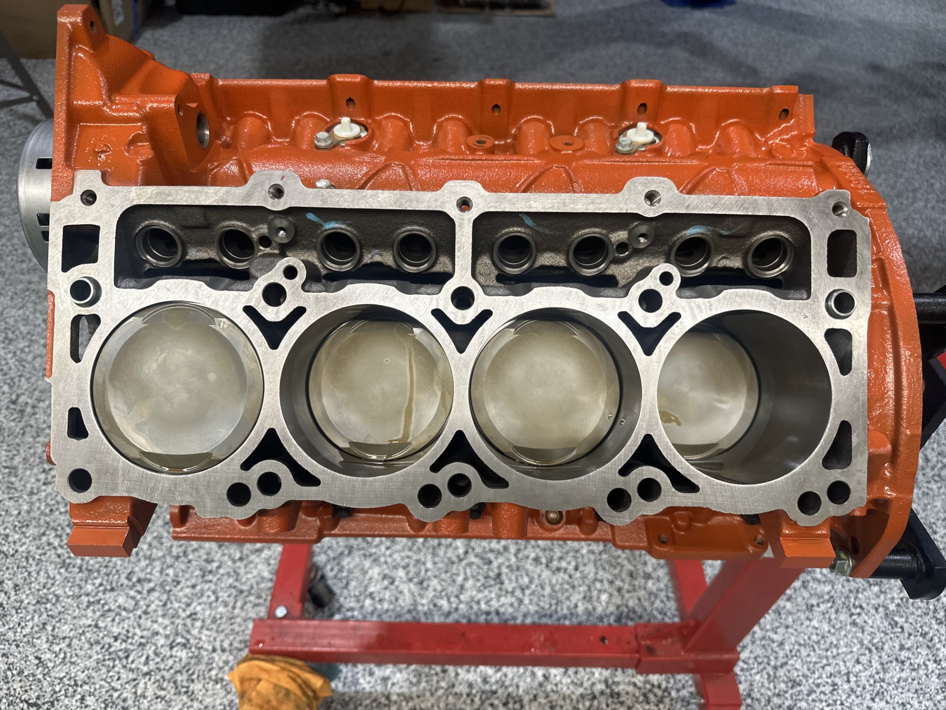 A red engine block with four pistons and two valves.