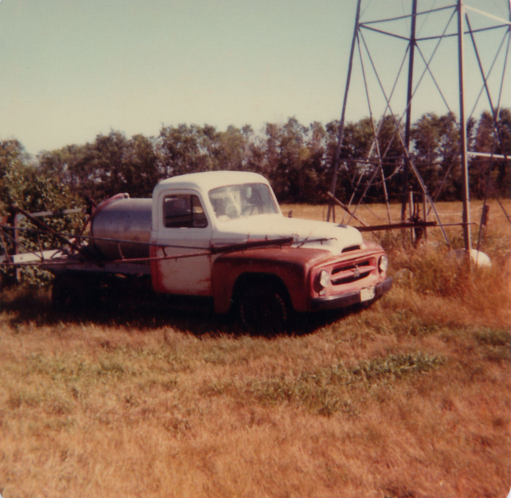 An old truck is parked in a field.