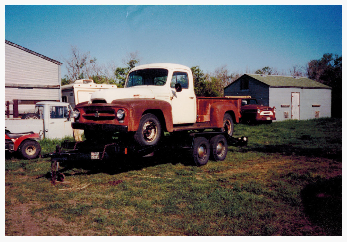 A truck is parked in the grass near other vehicles.